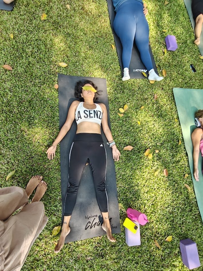 Student in Yoga Nidra practice at La Waha, lying on grass with eye pillow