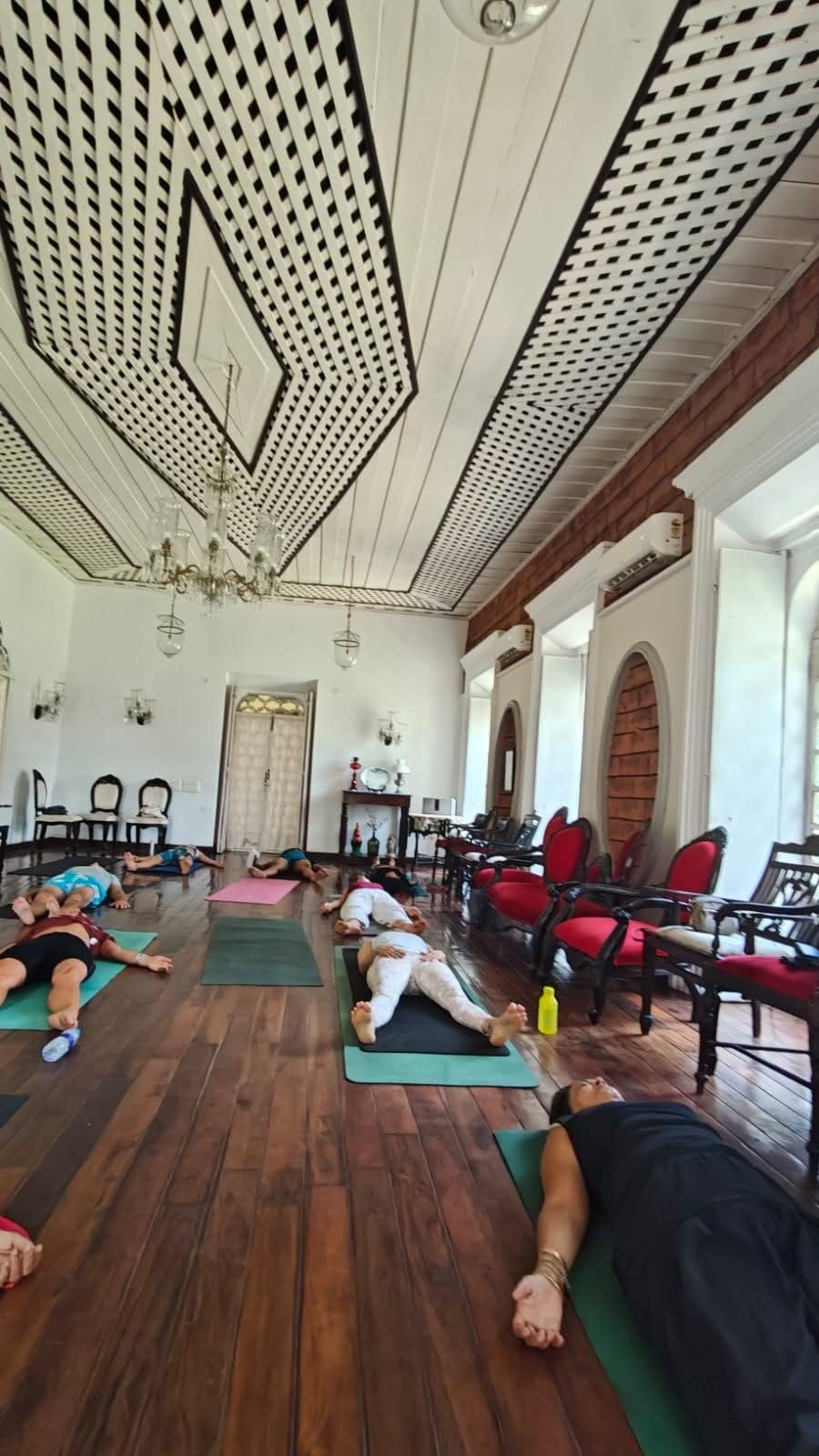 Indoor Yoga Nidra class at La Waha, Silva Heritage ballroom — students in Shavasana on wooden floors