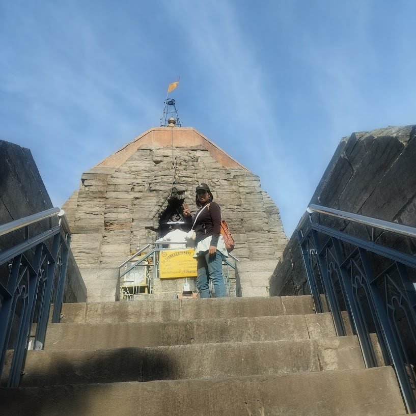 Varuna Shunglu at the top of the Shankaracharya Temple stone steps with the ancient stone structure behind her